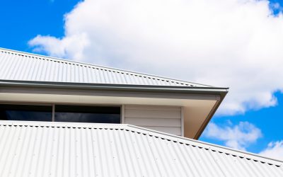 Closeup low angle view of corrugated iron roof of brand new house against blue sky with clouds, full frame horizontal composition with copy space