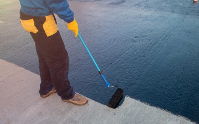 Roofer worker painting black coal tar or bitumen at concrete surface by the roller brush, A waterproofing. industrial worker on construction site laying sealant for waterproofing cement